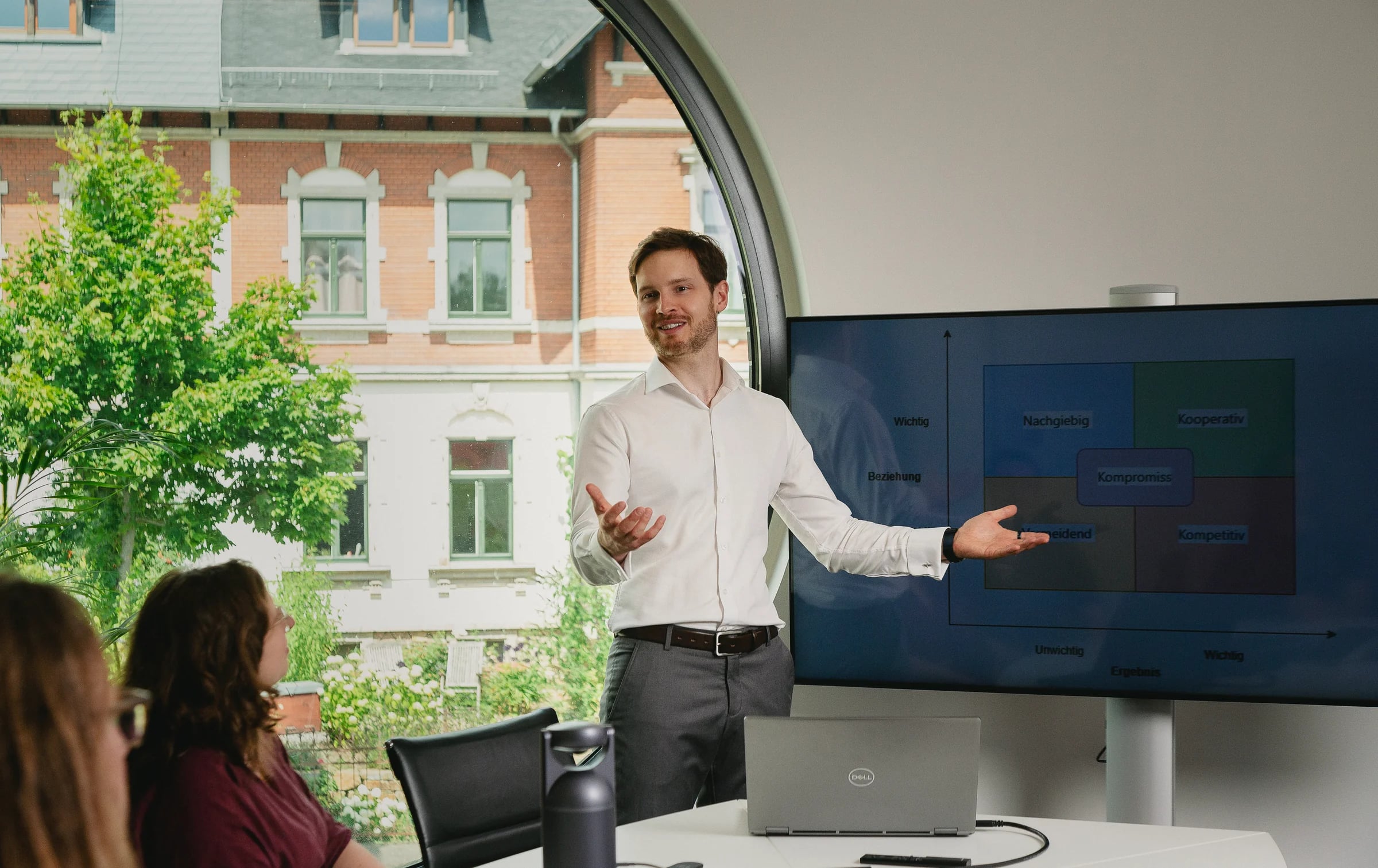 Seminarleiter am Rundfenster zeigt der Gruppe die Matrix der Verhandlungsstile auf dem Bildschirm.